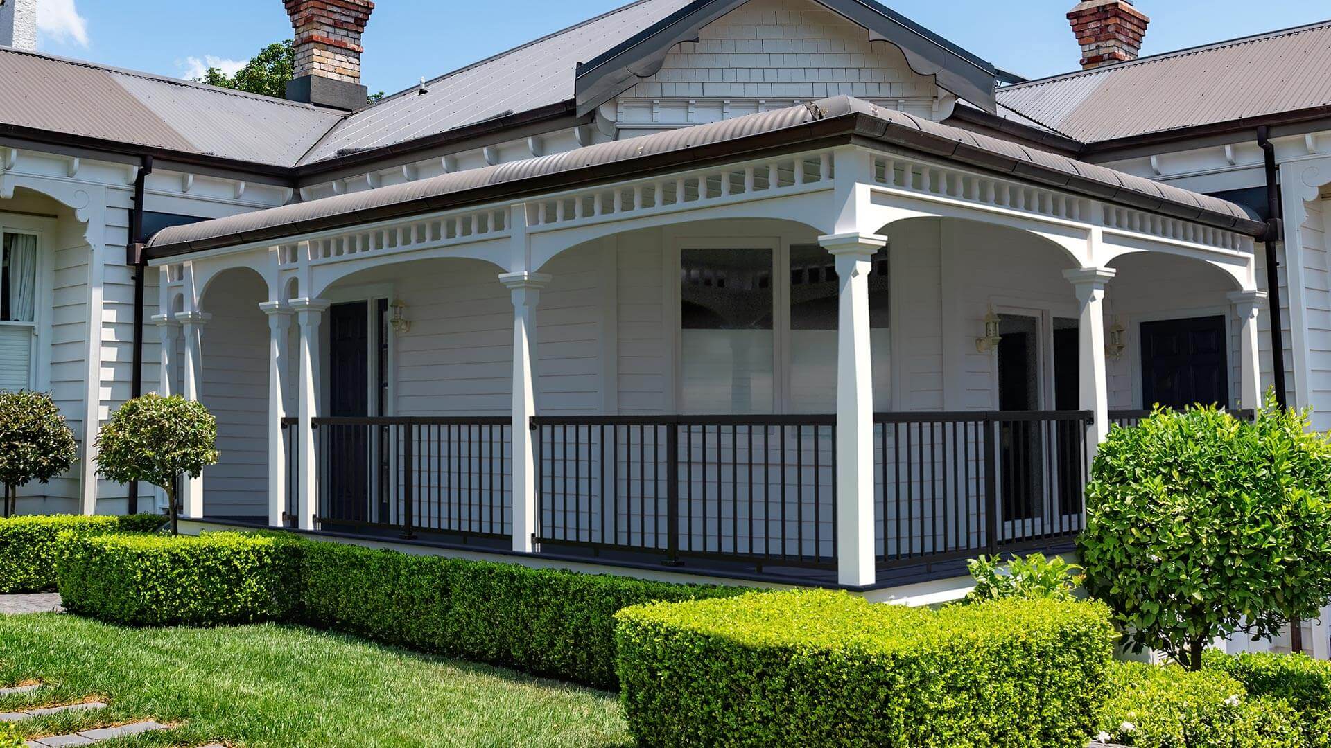 A front view of an Australian colonial house featuring a Peak Aluminium Balustrade with black regular balusters installed on the front porch.